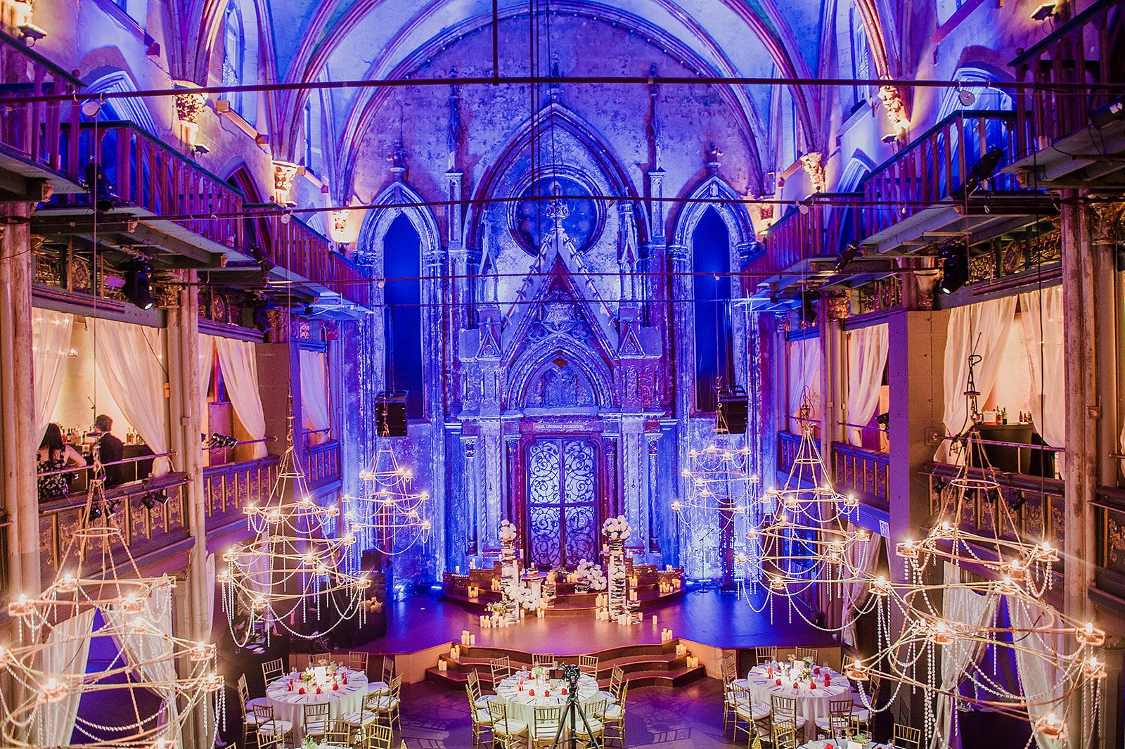 The nave in blue and violet, wire chandeliers over gold tables