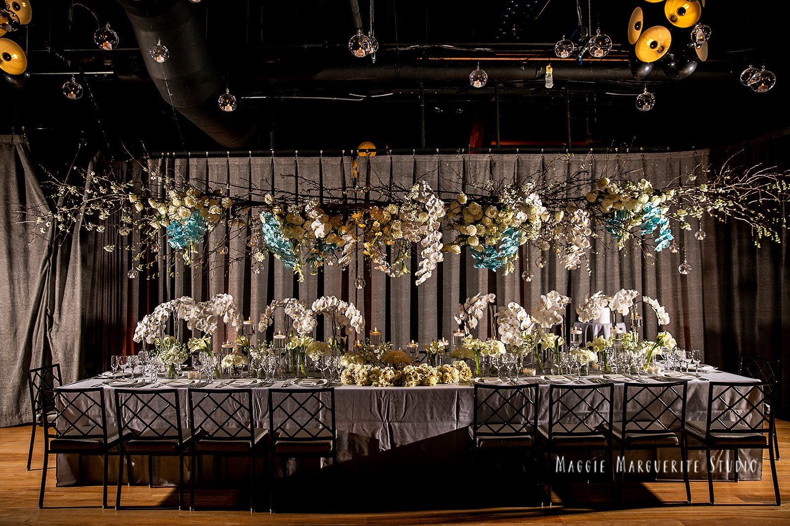 The head table dressed in white orchids, blue florals, and candlelight